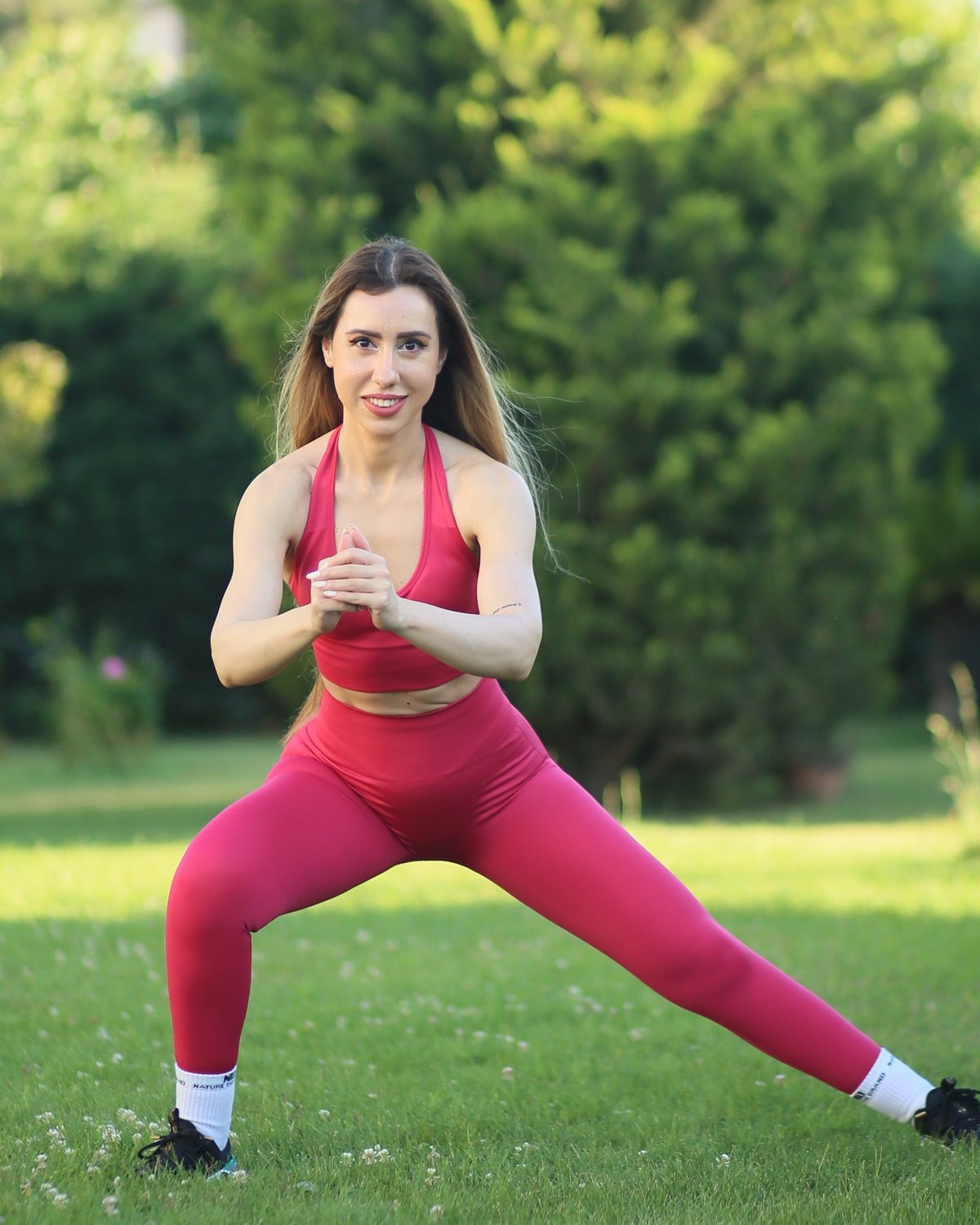 Parkta Nature The Brand pembe tayt ve sporcu sütyeni ile yan lunge yapan kadın